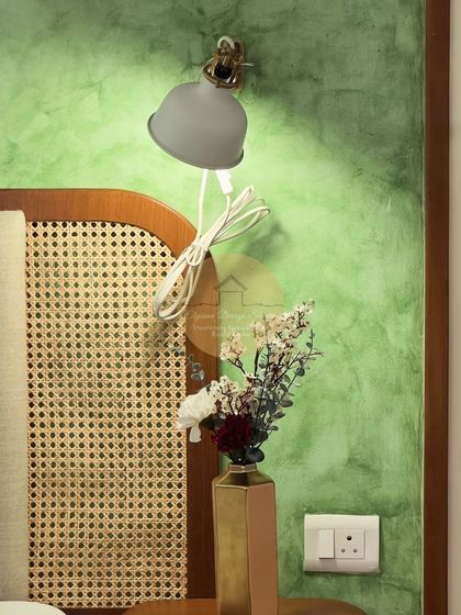 A detail shot of the reading lamp and cane headboard against the textured green wall, emphasizing the blend of materials and thoughtful design.