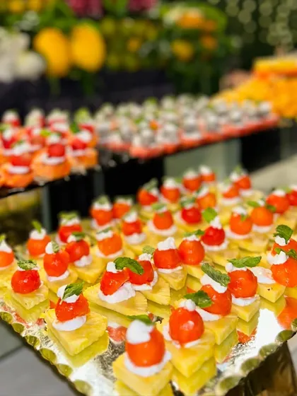 Bite sized fruit skewers are a healthy and refreshing dessert option. Here, pineapple cubes are topped with cherry tomatoes and a dollop of cream, creating a colourful and delicious bite.