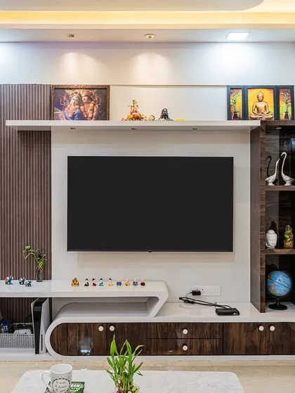 This custom TV unit combines open shelves for decor, closed cabinets for storage, and a mix of wood and white finishes. It’s a practical design that keeps the living room organized and stylish.