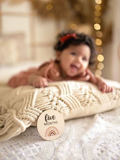 A happy five-month-old baby smiling, with the focus on the milestone marker. This shot perfectly captures the joy of reaching five months.