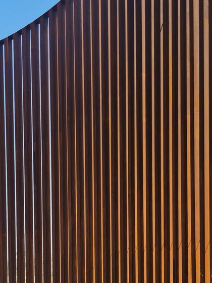 The vertical rhythm of the Corten steel fins creates a screen that is both solid and transparent, depending on the viewing angle.