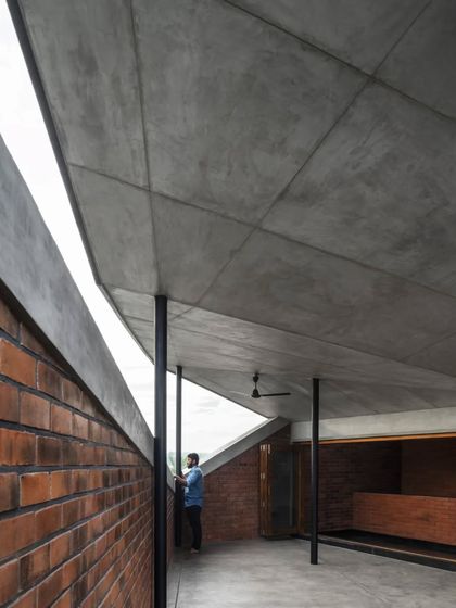 The upper level of the Brick House, where an angled concrete roof and clerestory windows create a dynamic, light-filled space overlooking the home's central void.