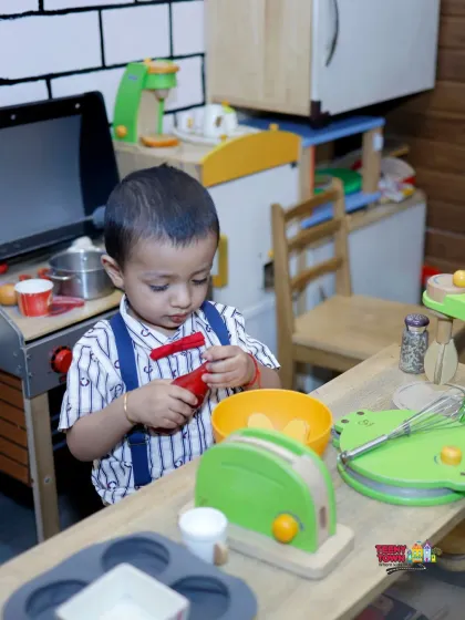 Even the tiniest guests have a world of their own to explore. This little chef is busy in our pretend play kitchen, a corner designed for imaginative fun for toddlers and young children.