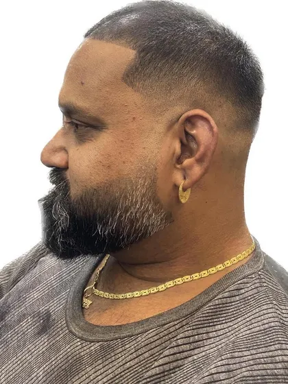 Even a simple buzz cut can be enhanced with a detailed fade. I gave this client a high fade that blends into his full beard, creating a strong, clean-cut, and powerful look.