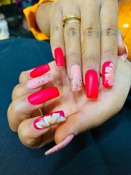 A vibrant set with bright pink nails and beautiful, hand-painted white and gold flowers.