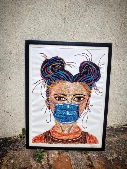 The completed and framed thread art piece, ready to be hung. The black frame provides a strong contrast to the colourful artwork.