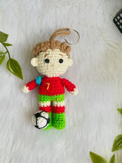 A mini replica doll of the football superstar Cristiano Ronaldo, CR7! This keychain-sized doll is ready for the field with his jersey and a tiny football.