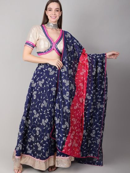 This dandiya night look features a royal blue printed skirt paired with an off-white blouse. The pink and blue trim on the blouse adds a pop of color that ties the whole ensemble together.