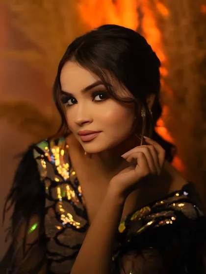 A slightly different angle of the glamour portrait, capturing a soft smile and the shimmer of the sequined outfit under the warm studio lights.