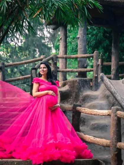 A beautiful solo shot of the mom-to-be on a rustic slide, with her magnificent pink gown cascading down.