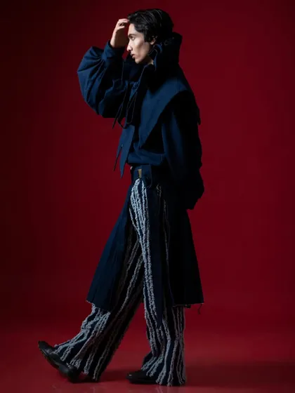 A profile shot in motion, capturing the flow and structure of the designer garment.