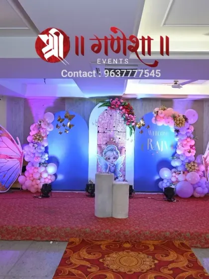 A wider angle of the butterfly-themed birthday stage. This view shows the full arrangement, including the large butterfly wing props, balloon garlands, and character cutouts, creating a complete and immersive fantasy world.