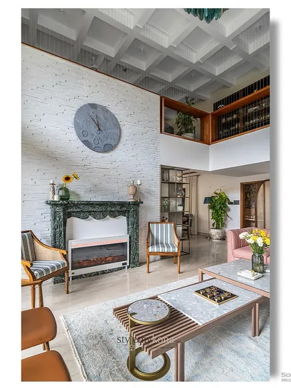 A vertical view of a living room with a striking green marble fireplace and a high, coffered ceiling. The eclectic mix of furniture, including striped armchairs and a pink sofa, adds a layer of personality and charm to this unique space.