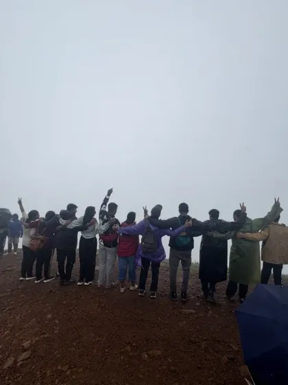 The team standing together with arms linked, overlooking a misty valley.
