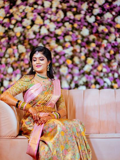 A serene portrait of the bride seated against a beautiful floral wall at her reception.