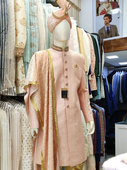 A peach sherwani for the groom, displayed on a mannequin with a matching turban and stole. This color is a great choice to complement many bridal lehengas.