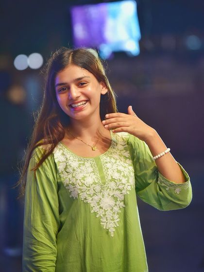 A playful and engaging portrait. Her gesture and bright smile, combined with the colorful background, create a very fun and lively image.