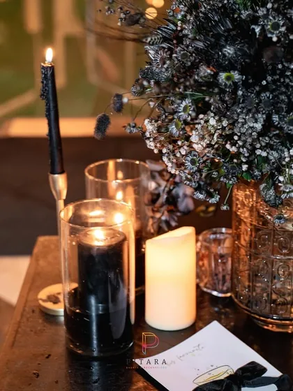 The warm flicker of candlelight against dark, textured elements. This close-up captures the moody, romantic ambiance we created with a combination of black candles, dark florals, and amber glass.