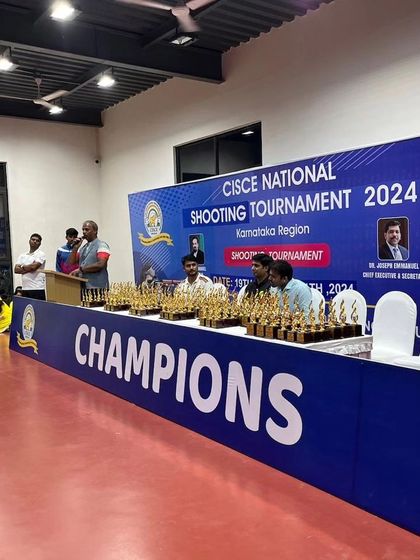 The awards stage, lined with trophies, ready for the closing ceremony of the CISCE National Shooting Tournament 2024.
