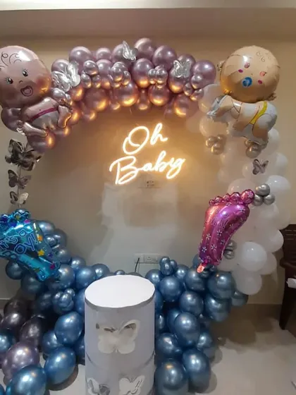 A glamorous "Oh Baby" shower decoration with a metallic theme. The balloon ring is made of shiny purple and silver balloons, with baby and butterfly foil balloons as accents.