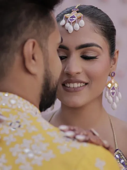 A close, romantic shot of the couple, where the bride's sleek hairstyle and maang tikka are highlighted.