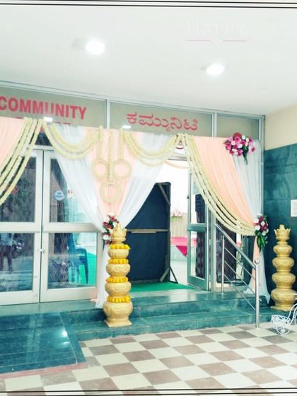 An elegant entrance decoration for a community hall, using soft peach and white drapes with floral accents. This design shows how even a simple space can be transformed into a graceful entry for a wedding or reception.