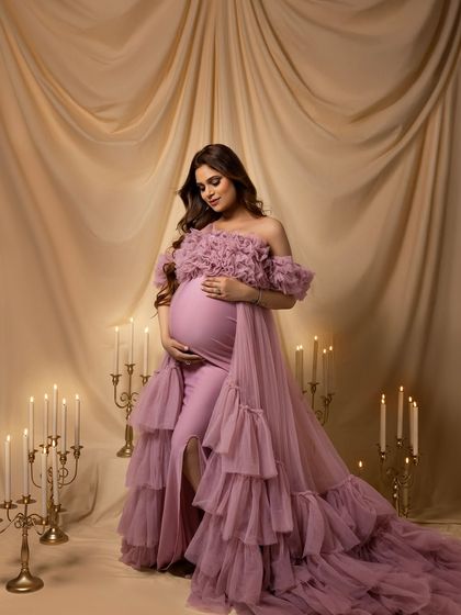 A regal, seated portrait in a dusty rose ruffled gown, surrounded by the romantic glow of candles.