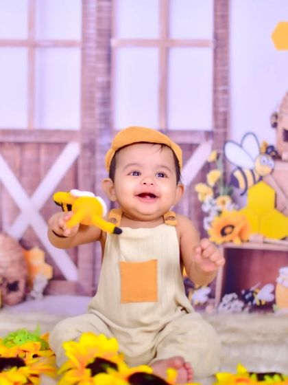 A happy baby in a honeybee-themed setup.