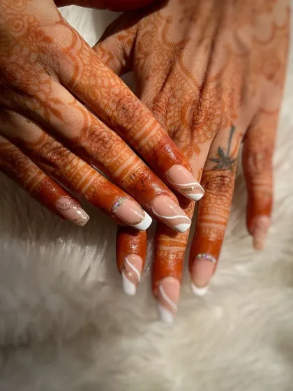 A clean and elegant French manicure with a swirl accent, perfectly complementing the bridal henna. This student work showcases precision and classic style.