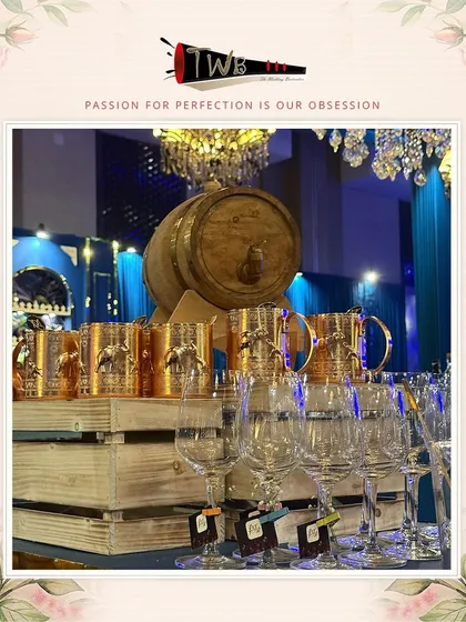 A stunning bar display featuring copper mugs and a barrel dispenser under opulent chandeliers.