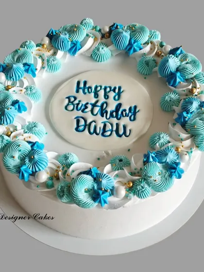 A simple yet beautiful birthday cake with a wreath of blue piped flowers. The design is elegant and perfect for celebrating a grandfather (Dadu).