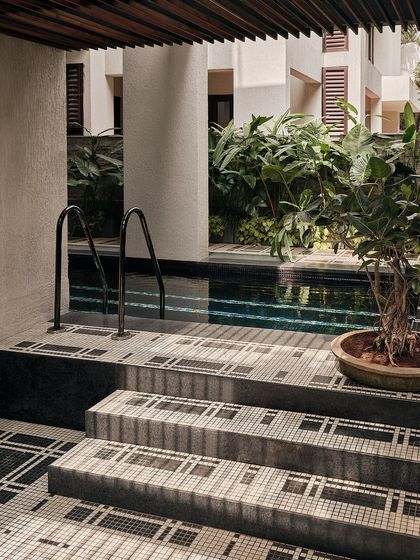 The steps leading down to the pool are clad in a beautiful black and white mosaic tile. The design creates a graphic, visually interesting transition from the deck to the water.
