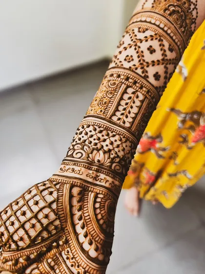 A close-up of a personalized touch: the couple's names beautifully written in Kannada script on the wrist.