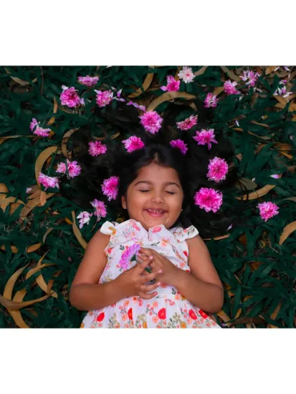A blissful smile from a girl lying in the grass, with flowers in her hair. A perfect example of a beautiful, natural portrait.