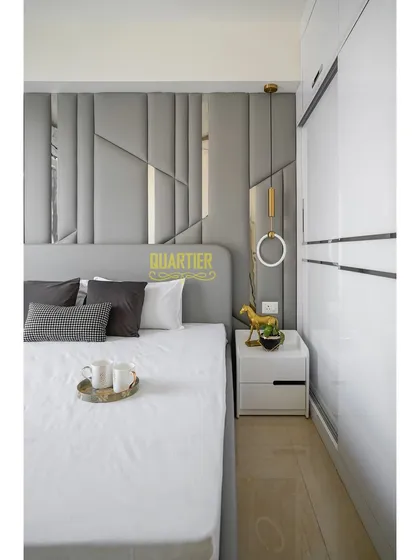 A view of the guest bedroom showing the sleek, white sliding wardrobe next to the bed. The clean lines and reflective surface help to make the room feel spacious and bright.
