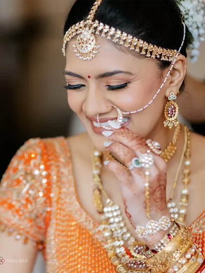 A close-up of the bride's joyful smile, capturing her happiness and the intricate details of her bridal jewelry and nath.