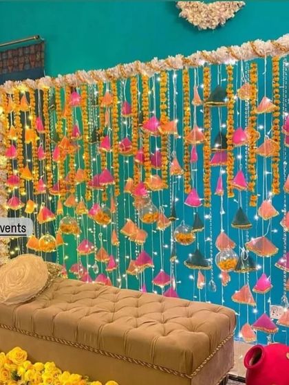 This creative Mehndi backdrop uses hanging gota patti triangles and glass baubles against a teal curtain, creating a unique and shimmering photo opportunity.