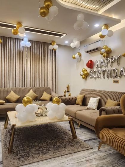 A sophisticated decoration for a 75th birthday celebration at home. The gold and white balloons on the ceiling and wall create an elegant and celebratory feel without being overwhelming.