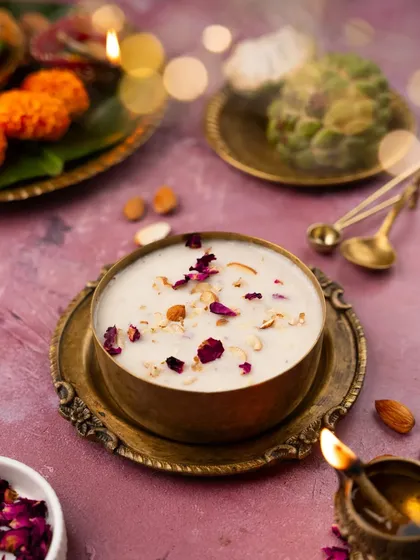 A festive shot of kheer in a traditional brass bowl, surrounded by diyas and marigold flowers. This image was created to celebrate Navratri, capturing the sweet, comforting essence of the festival.