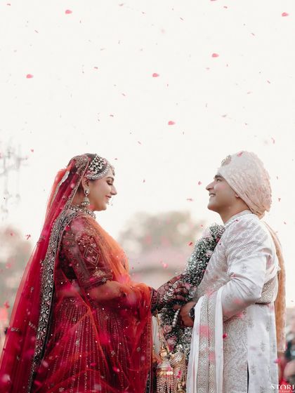 A romantic shot of the couple looking at each other under a shower of petals, capturing a perfect moment of love.