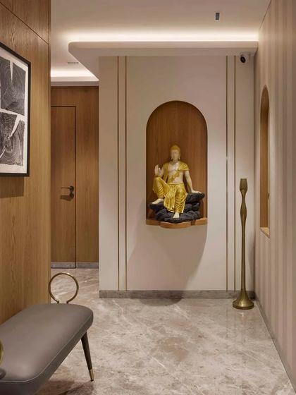 The entrance to this home sets a spiritual and welcoming tone. A serene Buddha statue sits in a warm, illuminated niche, creating a sense of calm from the moment you step inside. The wood paneling and striped wallpaper add texture and depth.
