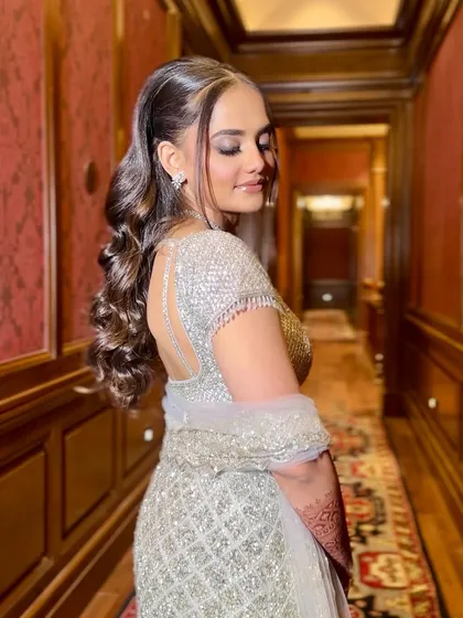 A side profile showing the beautiful hairstyle and the back of the glamorous lehenga. The entire look is pure elegance.