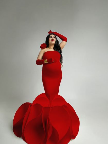 Looking towards the future with grace and confidence. This pose, with the hat removed, highlights the mother's joyful expression and the elegant lines of the red gown. It's a portrait of hopeful anticipation.