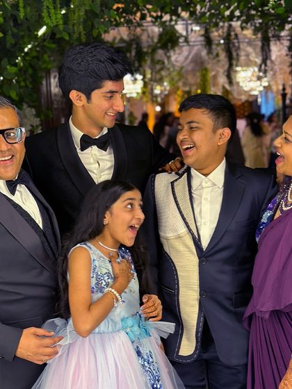 A family portrait where dapper elegance meets unconventional flair. The two brothers, one in a classic tuxedo and the other in a unique deconstructed jacket, showcase their individual styles while looking perfectly united.