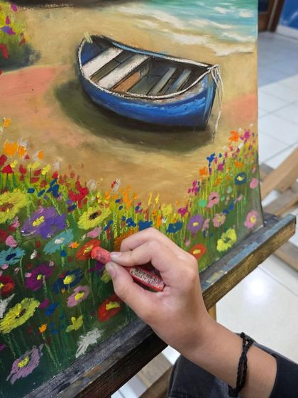 This macro shot shows the rich texture of the oil pastels as the student applies them to the paper to create a field of flowers.