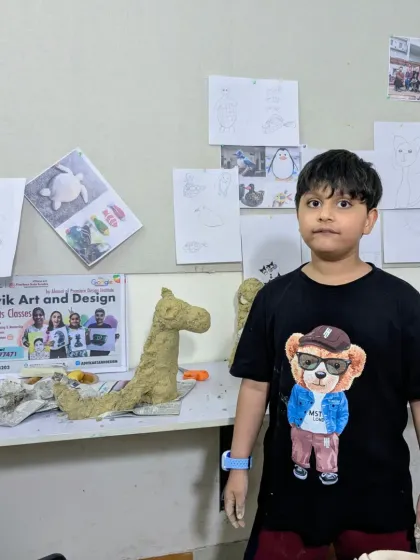A young artist stands next to his work-in-progress giraffe sculpture. We start with simple shapes and slowly build up the details.