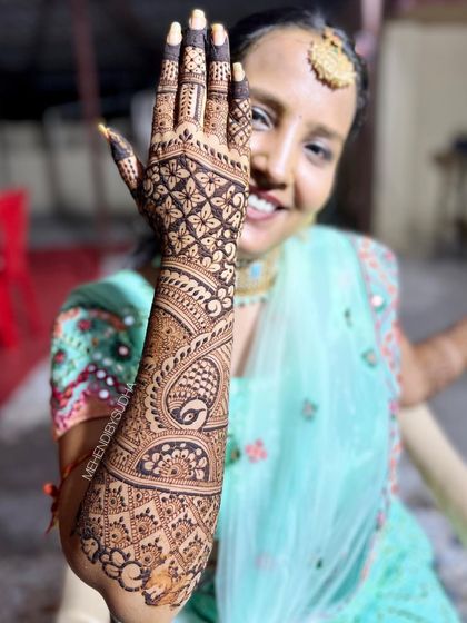A beautiful shot of a bride showing the back of her hand, adorned with a classic peacock and paisley design.