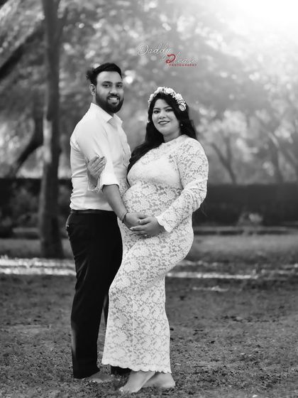 A lovely black and white couple's portrait taken outdoors. The soft backlighting creates a beautiful halo effect, making this a romantic and memorable pregnancy photo.