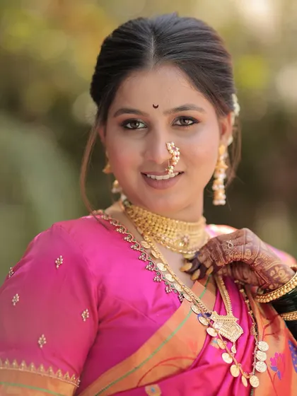 A close-up portrait of the happy bride, showing her flawless makeup and traditional nath.