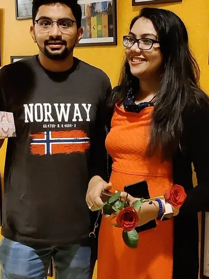 Celebrating a special occasion with us! This couple is holding roses and a gift, posing in front of our movie poster wall. It’s the perfect spot to capture memories of your celebration.